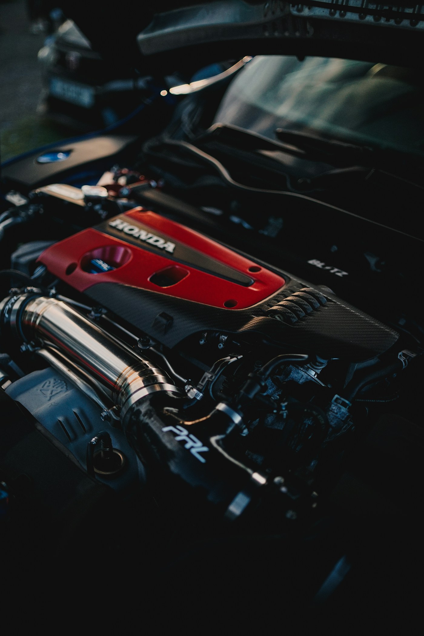 Car engine bay with visible valve cover and intake components